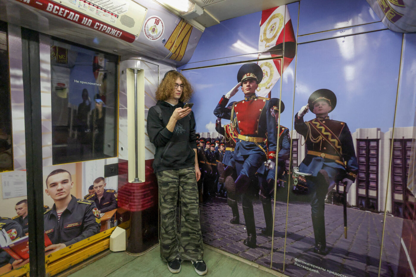 Пассажир метро разговаривает по мобильному телефону в тематическом поезде Росгвардии в Москве
